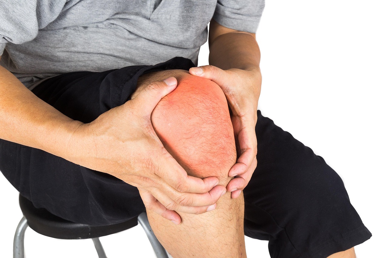 Person holding a red, inflamed painful knee, representing arthritis and chronic joint pain